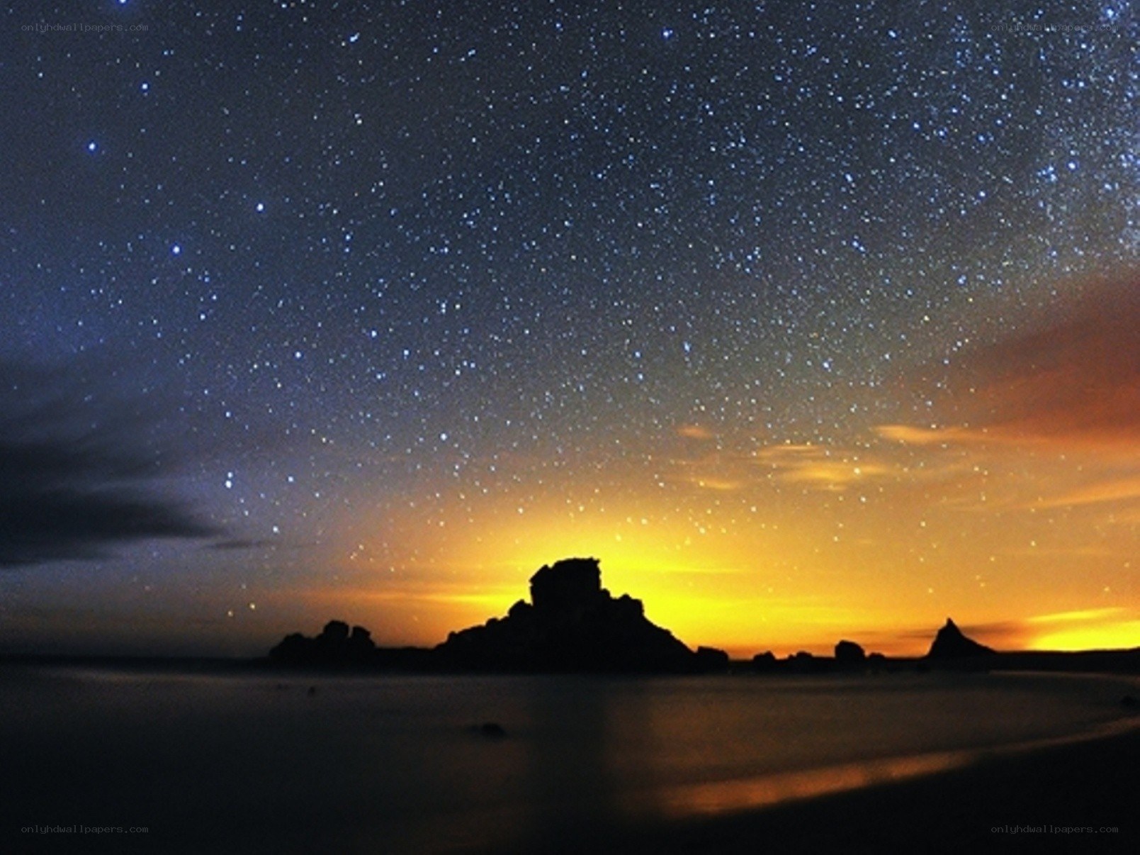 Starry night over rocky coastline