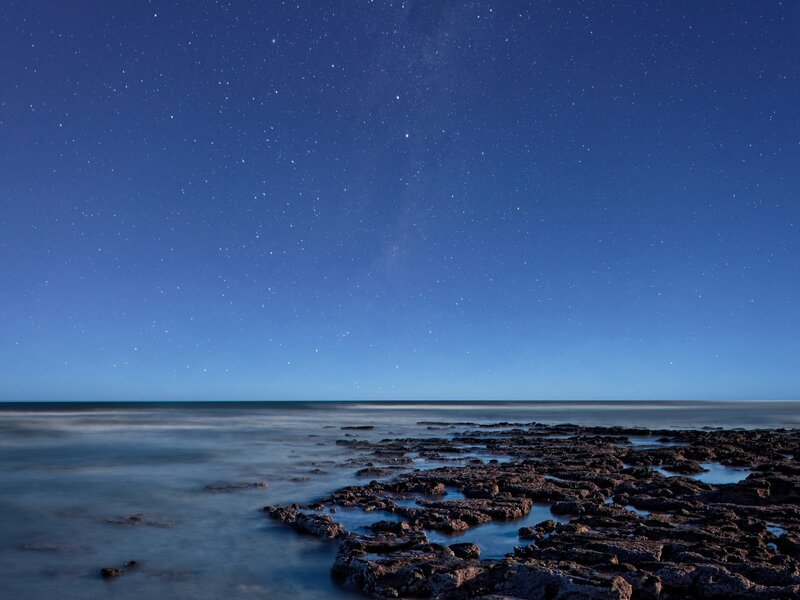 Starry night over rocky shore