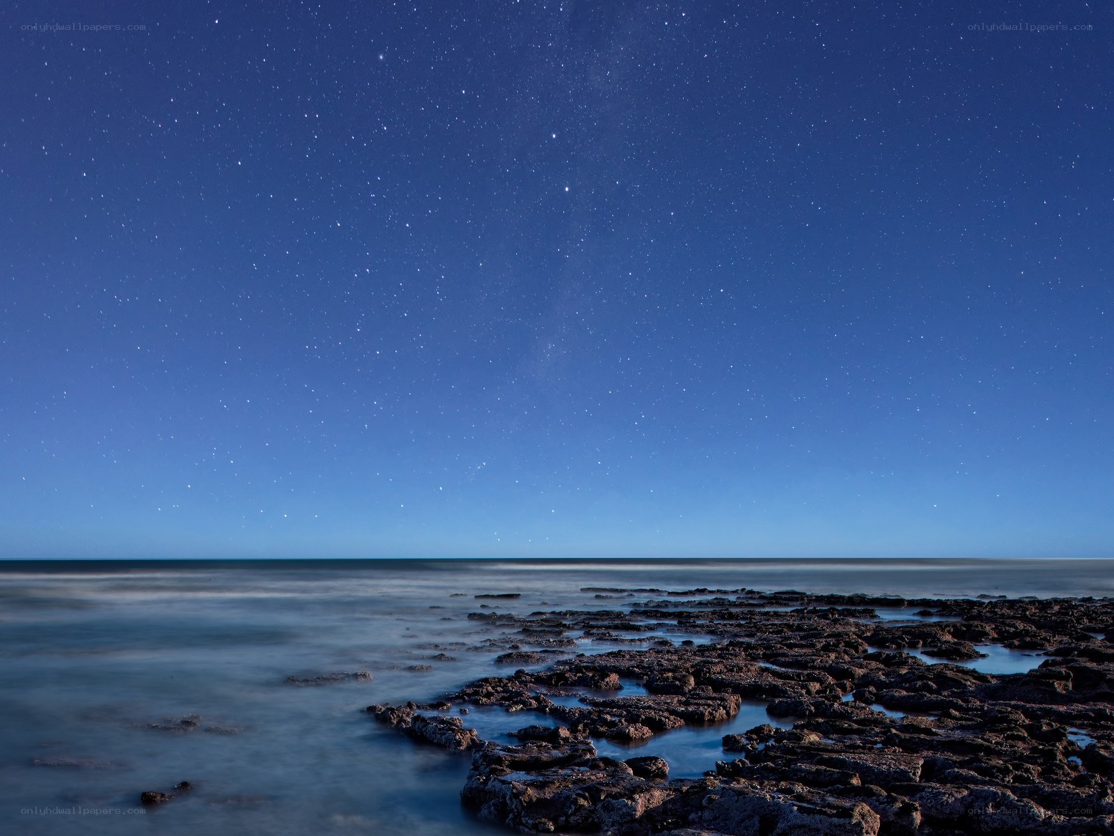 Starry night over rocky shore