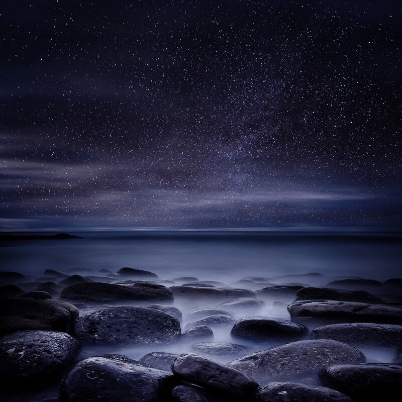 Starry night over rocky shore