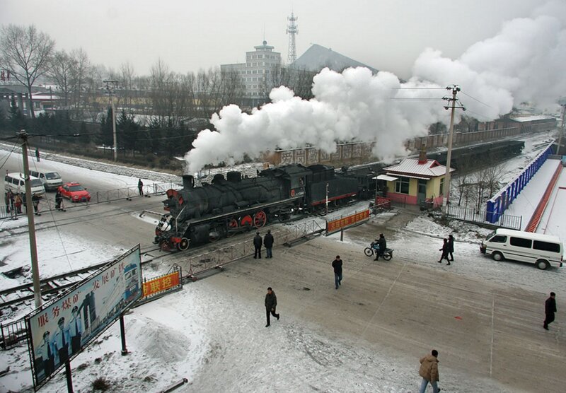 Steam train at snowy railway crossing