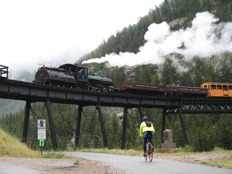Steam Train on Bridge — Green, Serene, Afternoon, Photograph, Bicyclist