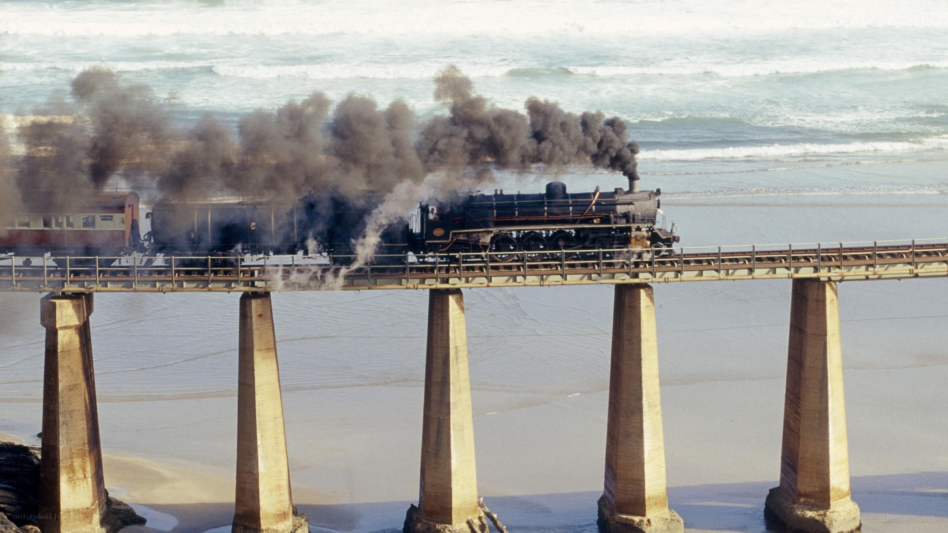 Steam train on coastal bridge