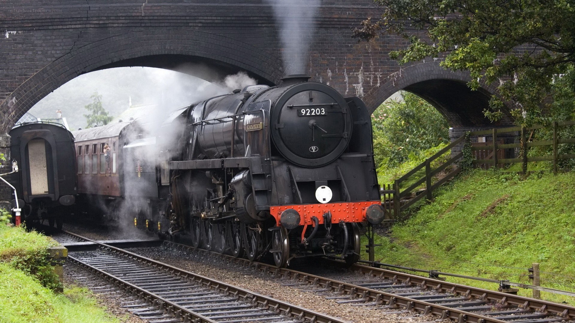 Steam train under a bridge