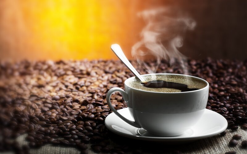 steaming coffee cup on beans