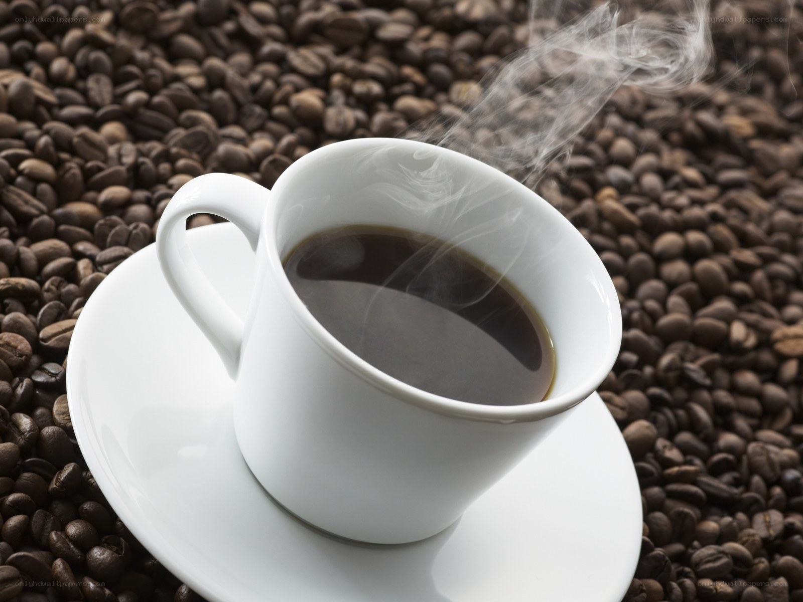 steaming coffee cup on beans
