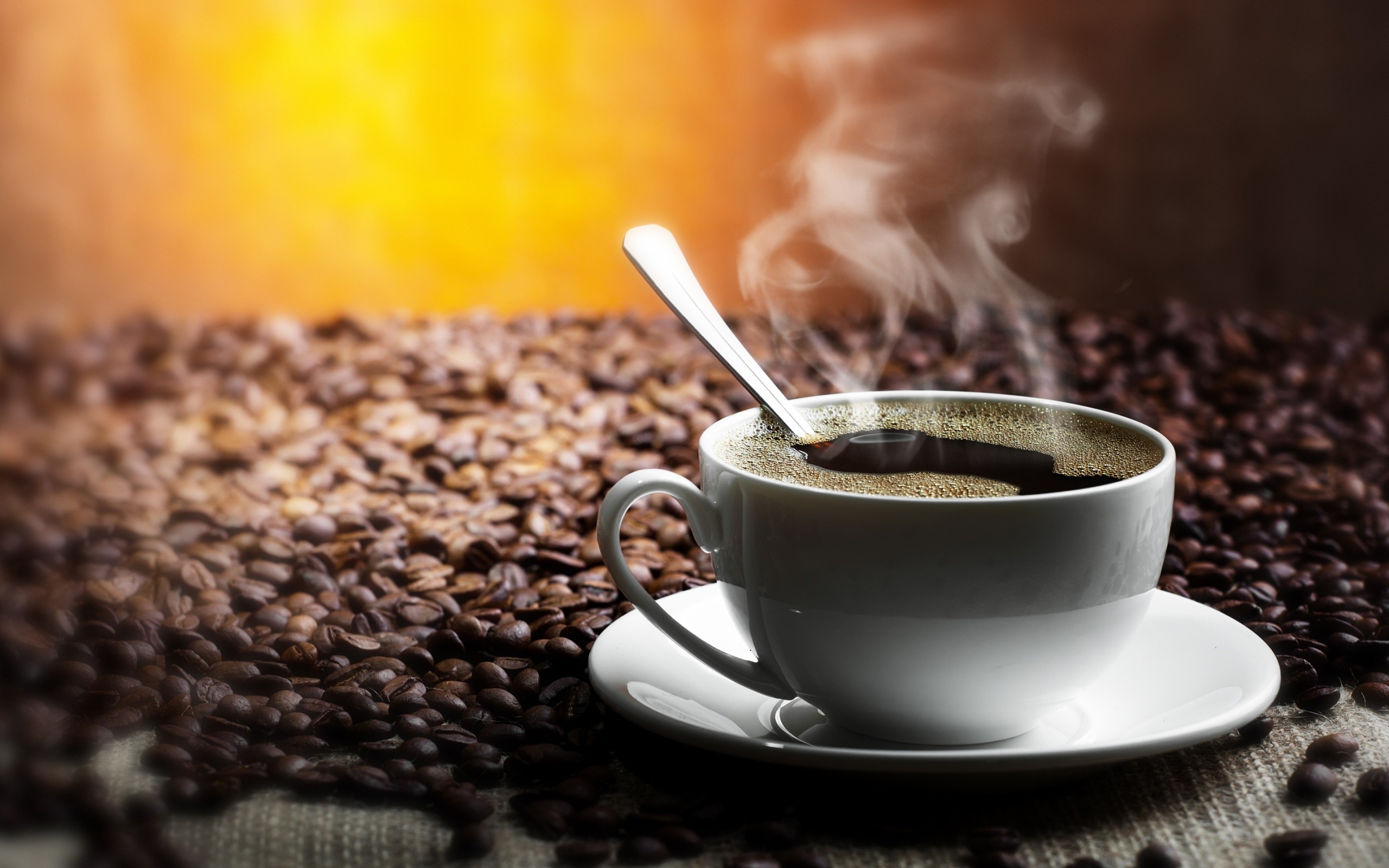 steaming coffee cup on beans
