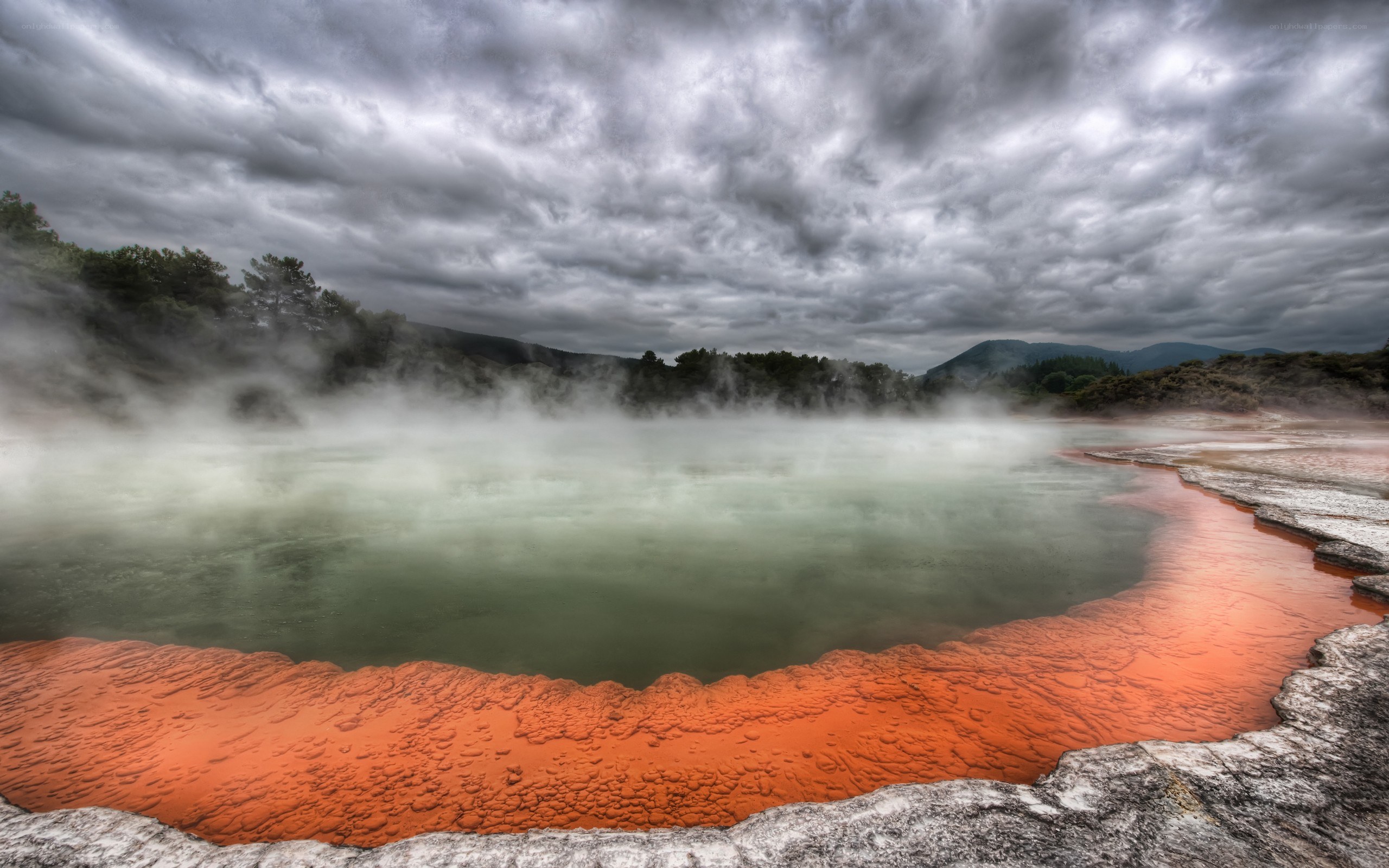 Steamy geothermal pool under cloudy sky