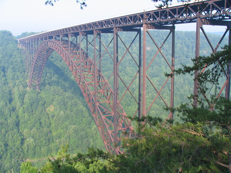 Steel arch bridge over forested canyon