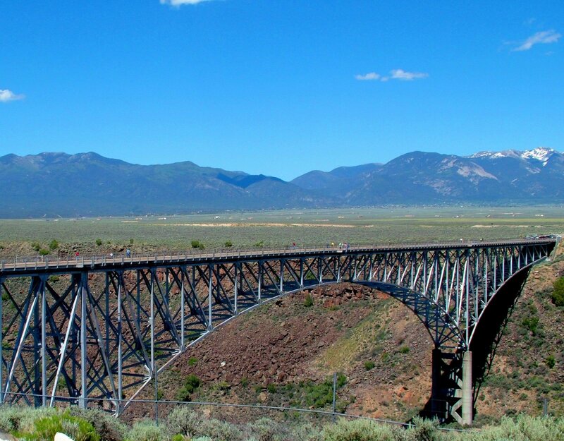 Steel bridge over canyon with mountains