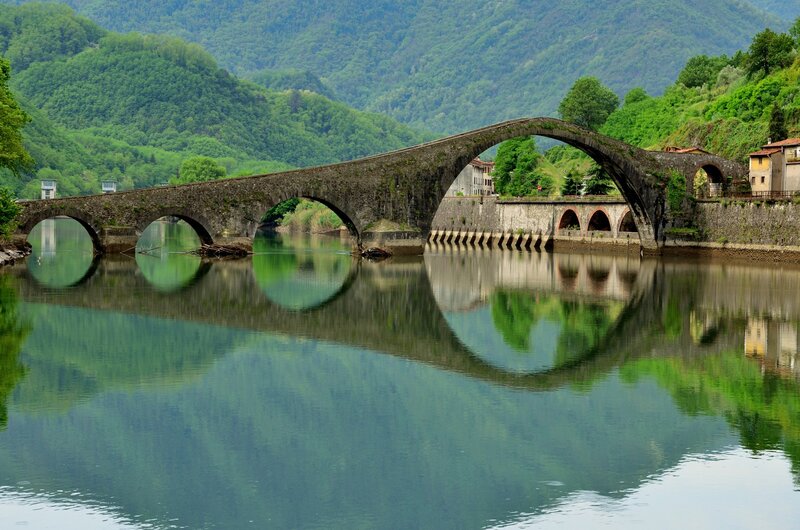 Stone Arch Bridge — Green, Serene, Afternoon, Photograph, River, Mountains, Buildings