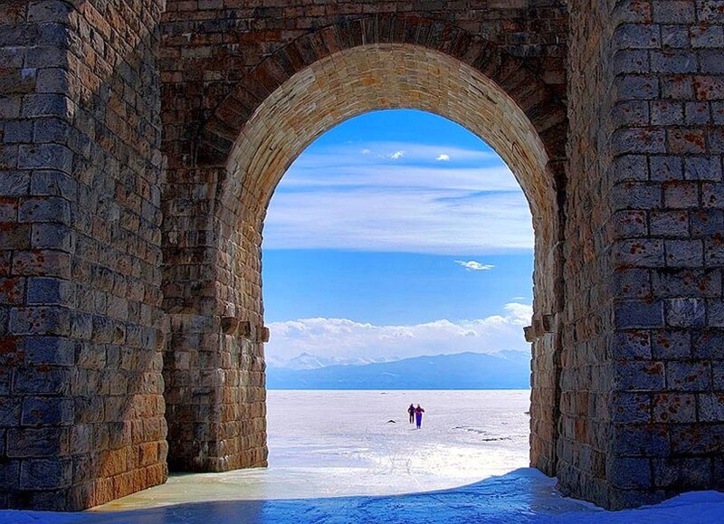 Stone arch framing a frozen lake