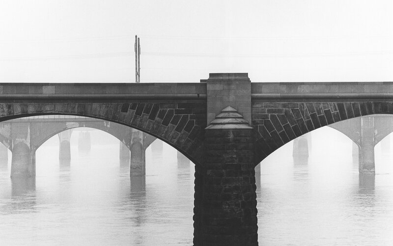 Stone bridge over foggy river