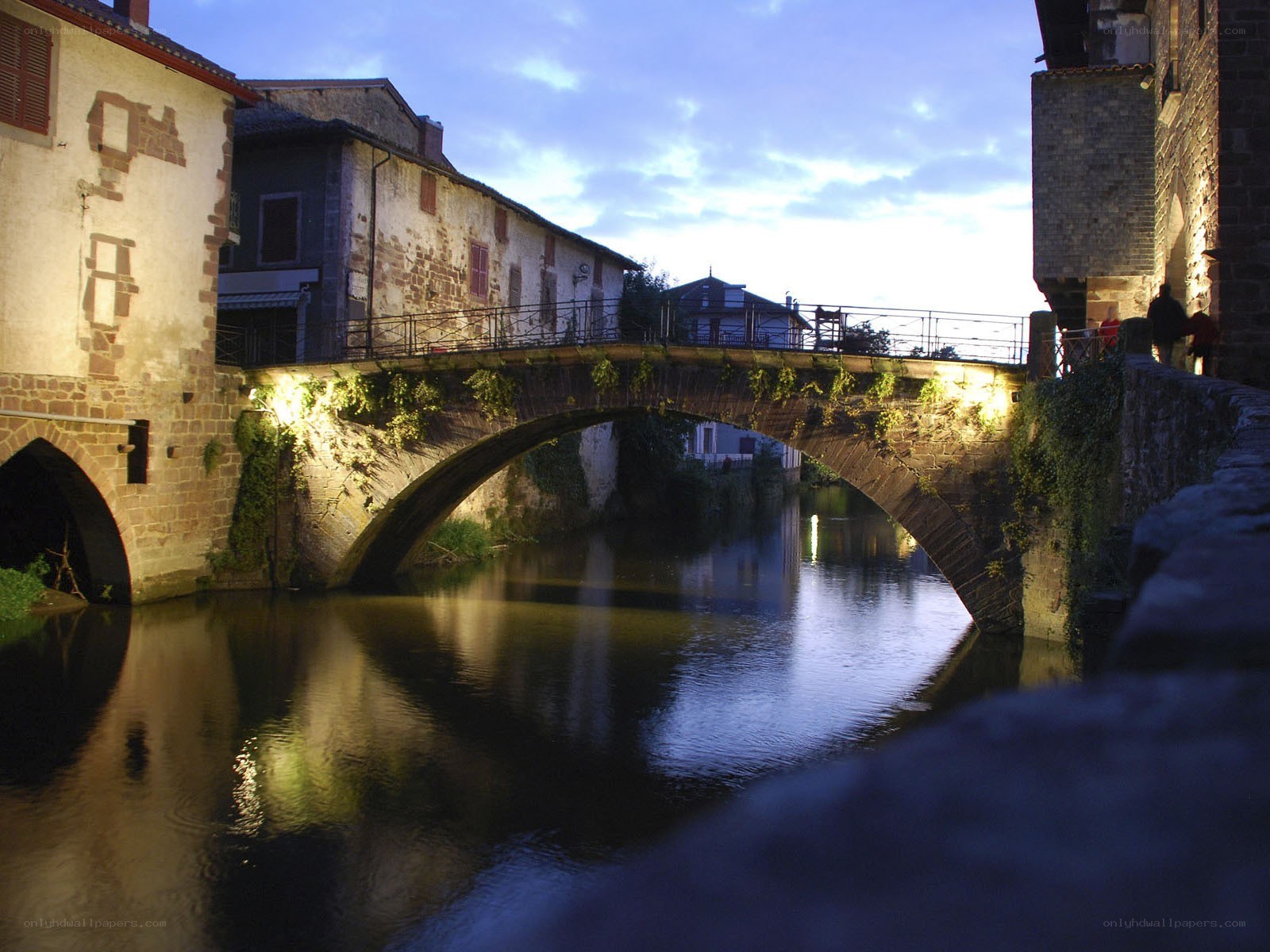 Stone bridge over river at dusk