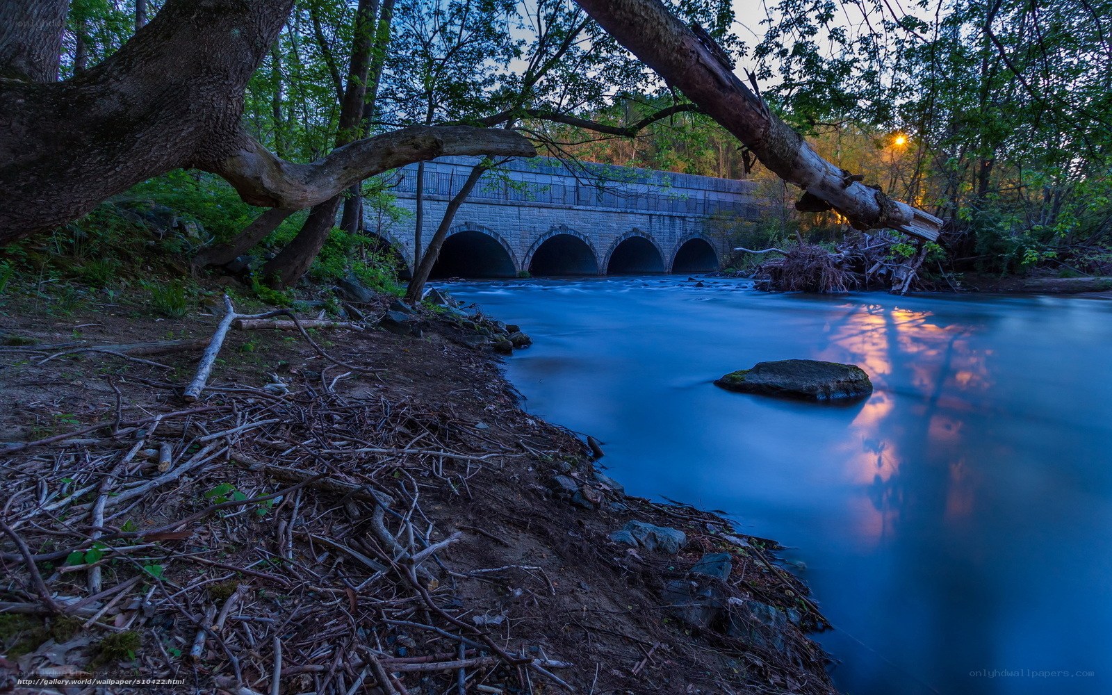 Stone bridge over river at dusk