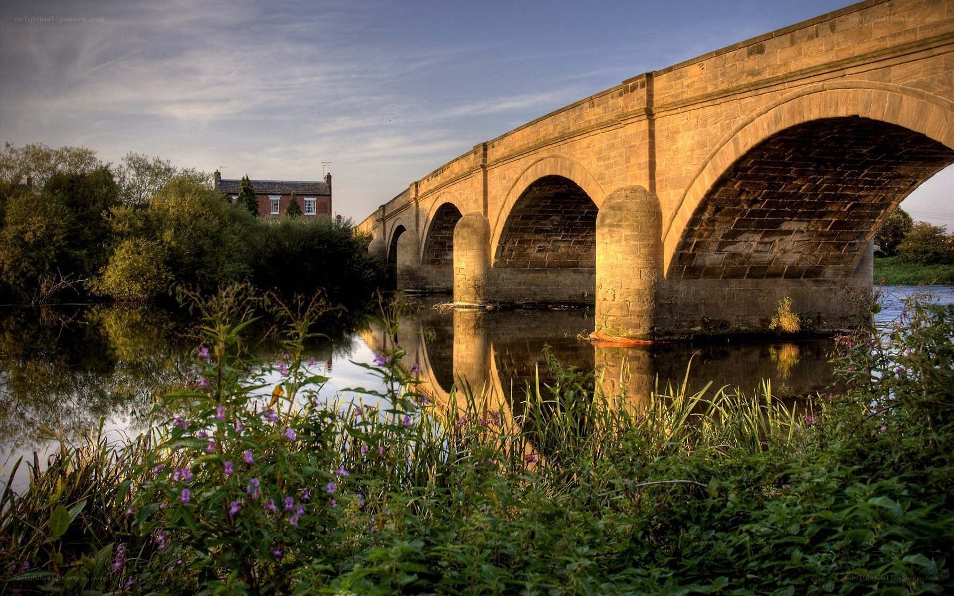 Stone bridge over river at sunset