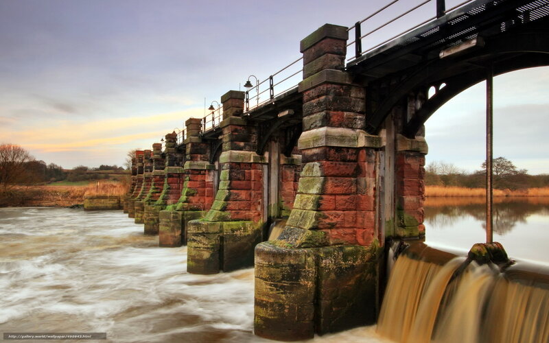 Stone bridge over river at sunset