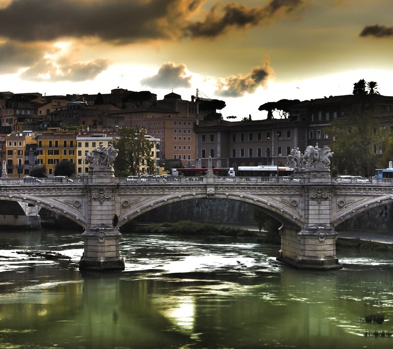 Stone Bridge over River — Green, Dramatic, Sunset, Photograph, City Buildings