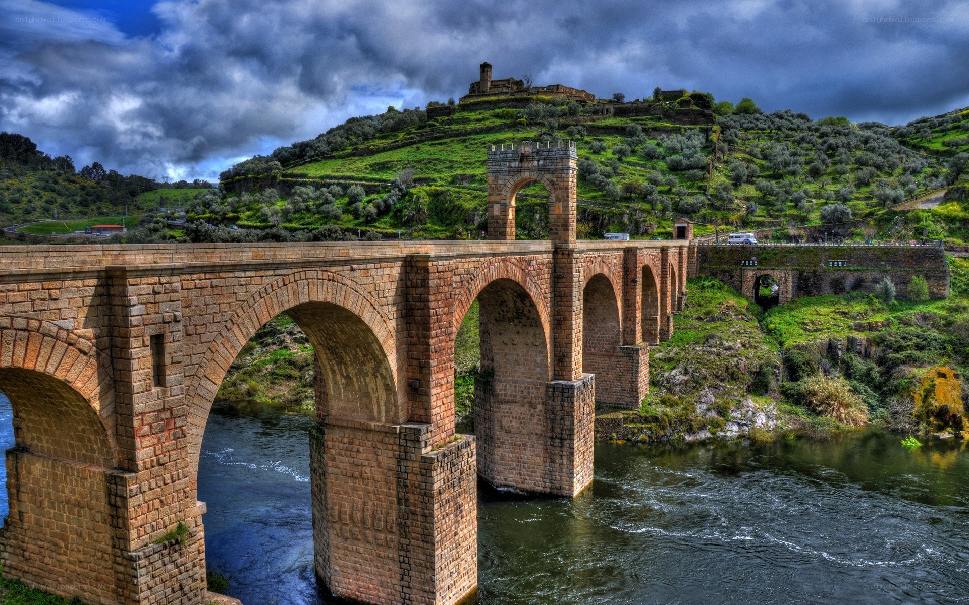 Stone bridge over river with hilltop castle