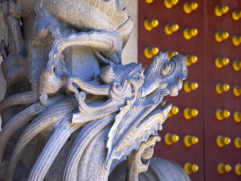 Stone dragon sculpture near red door