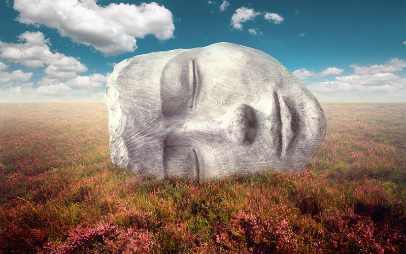Stone face sculpture in field