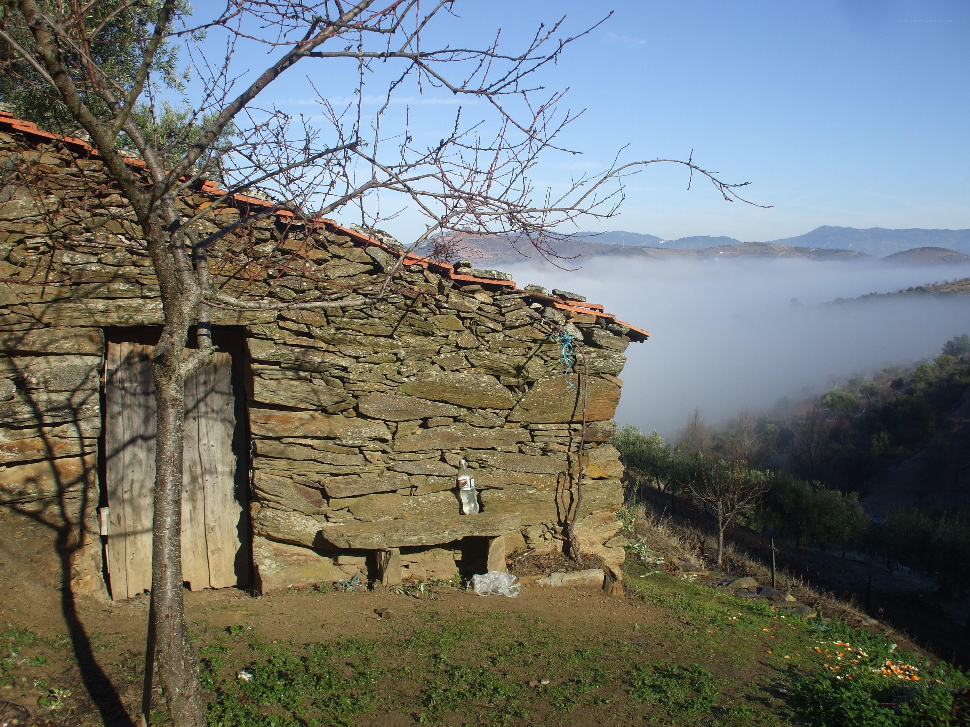 Stone hut overlooking foggy valley