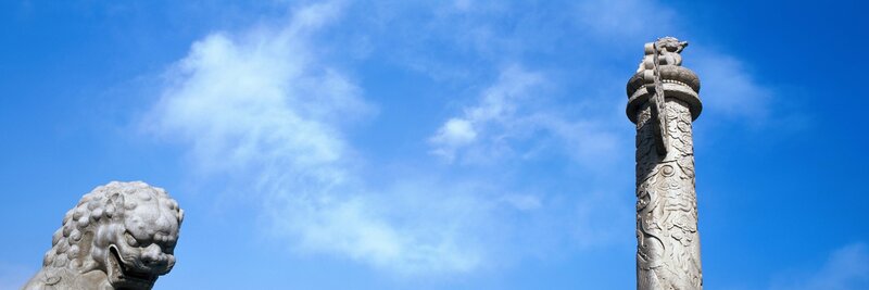 Stone lion and pillar against blue sky