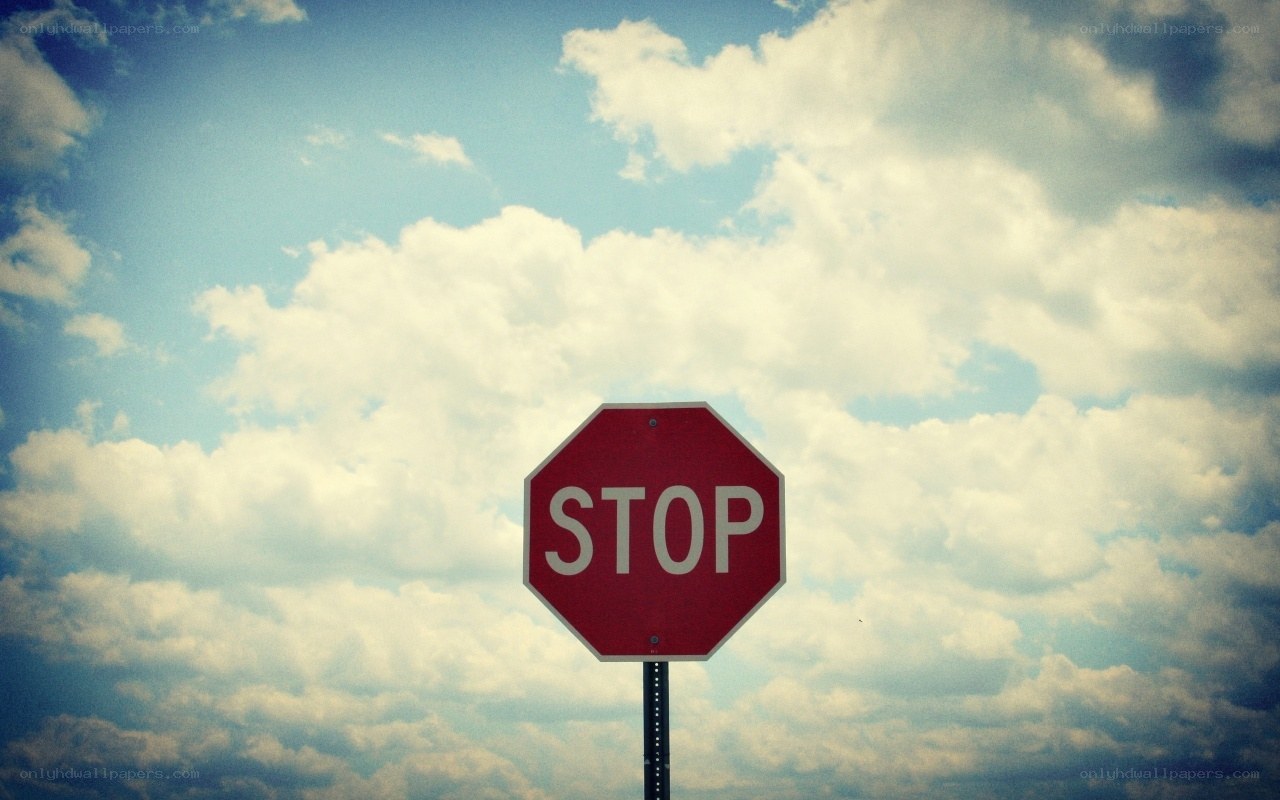 Stop sign against cloudy sky