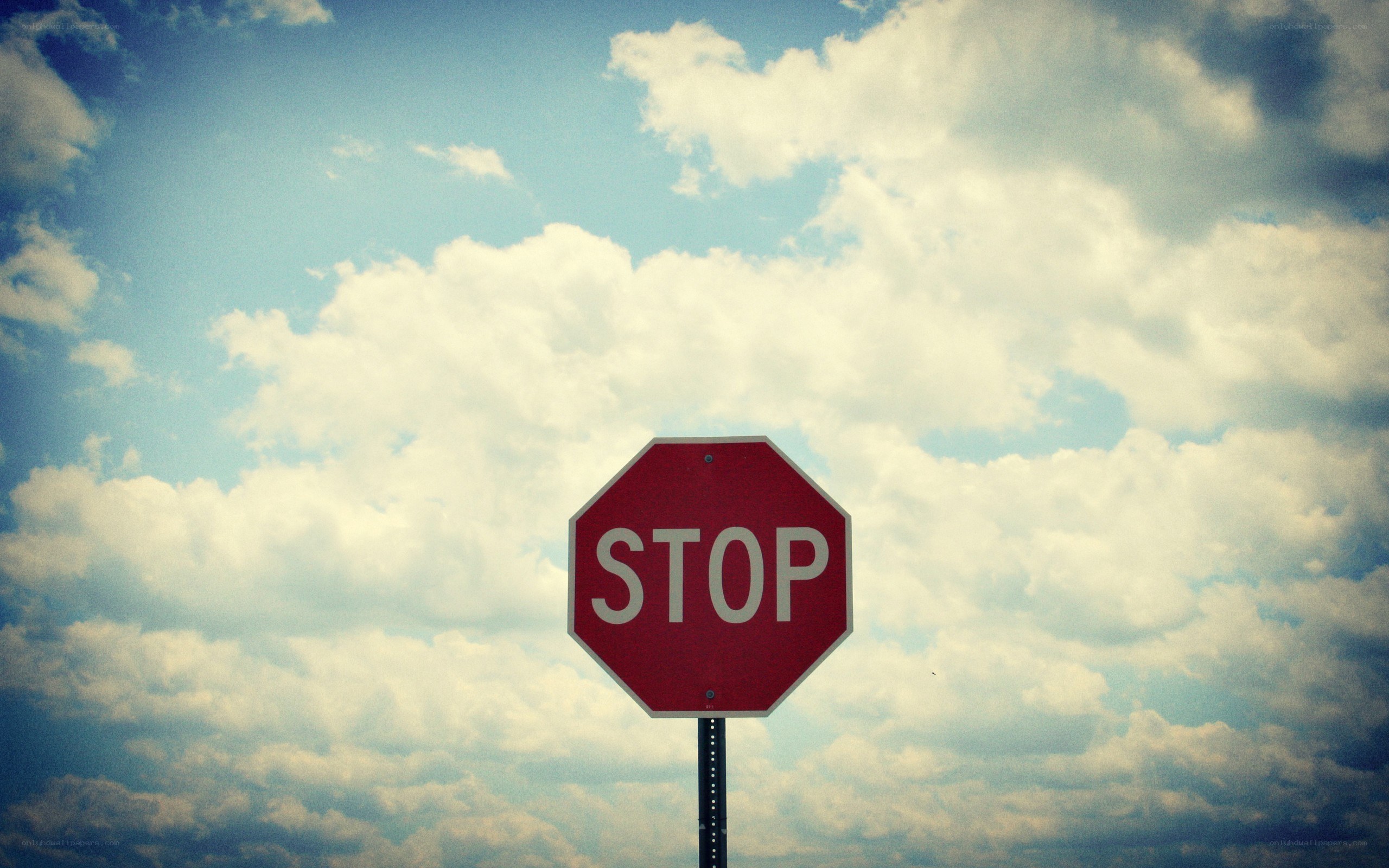 Stop sign against cloudy sky