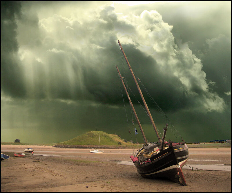 Stormy sky over beached sailboat