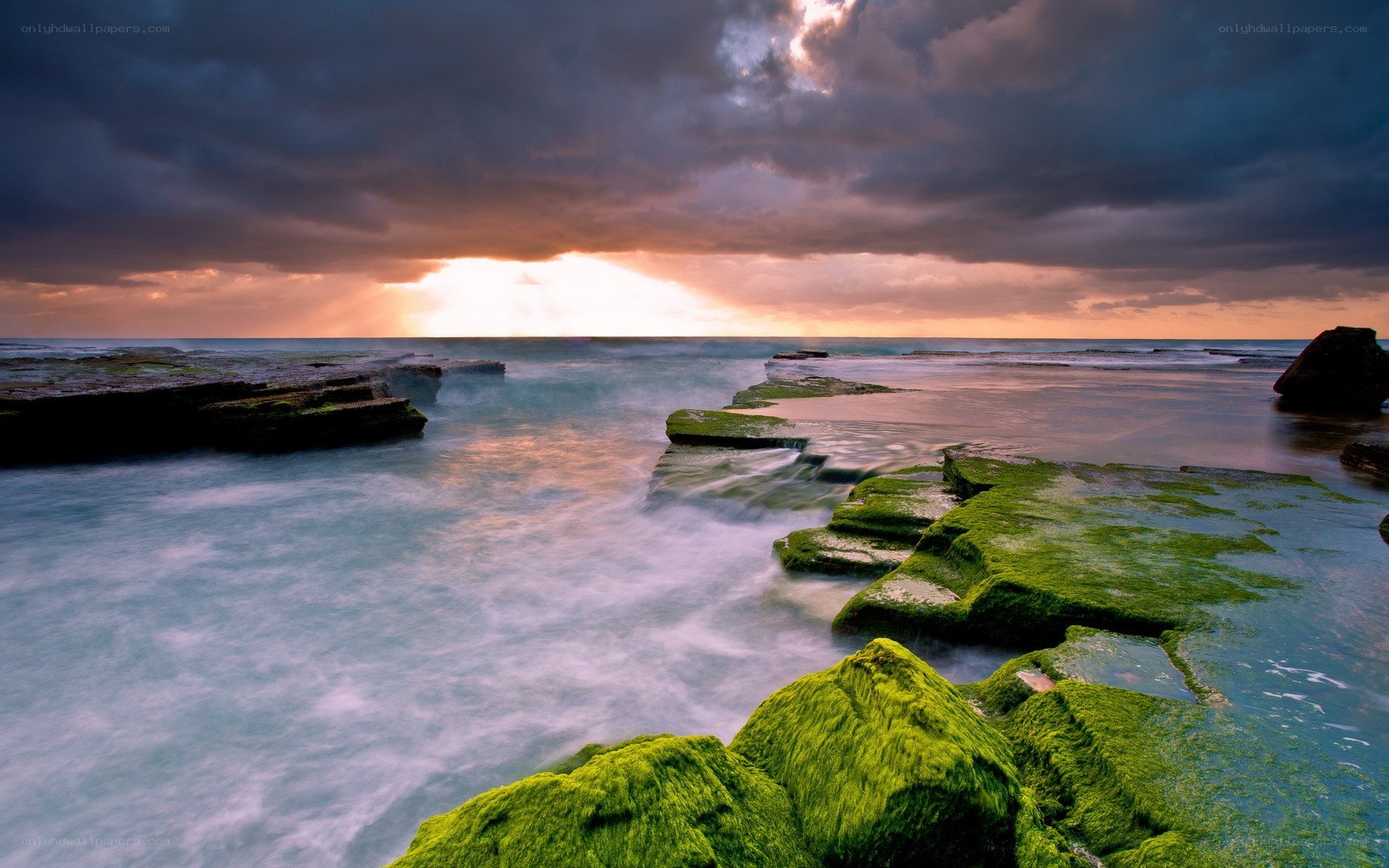 stormy sunset over mossy rocks