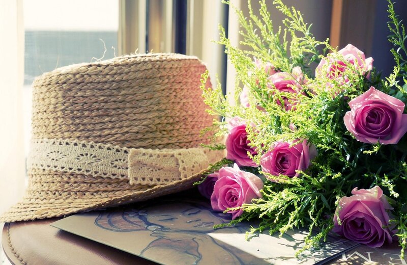 Straw hat and roses on table