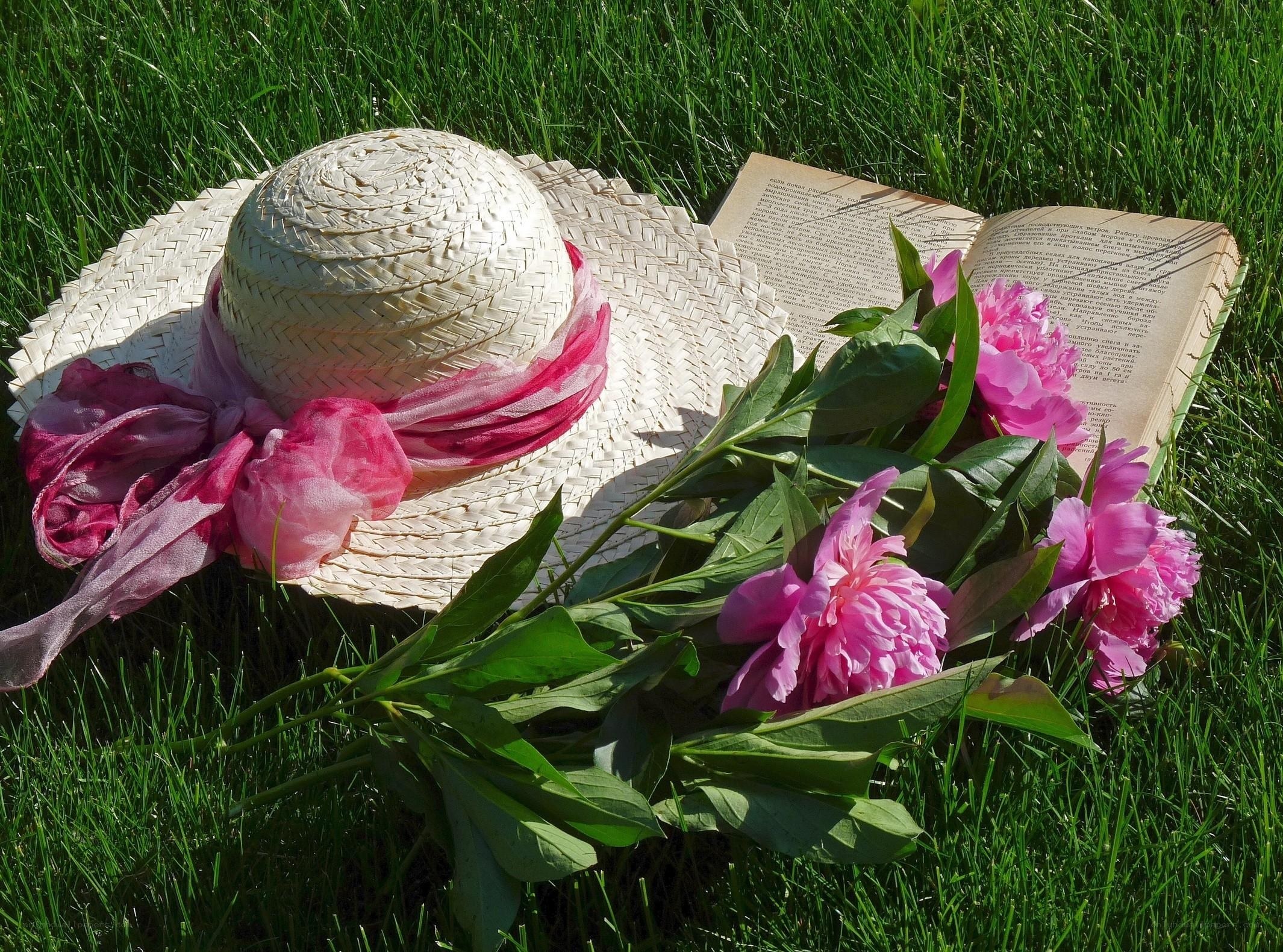 Straw hat with peonies on grass