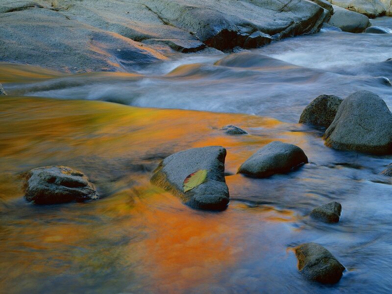 Stream flowing over rocks at sunset