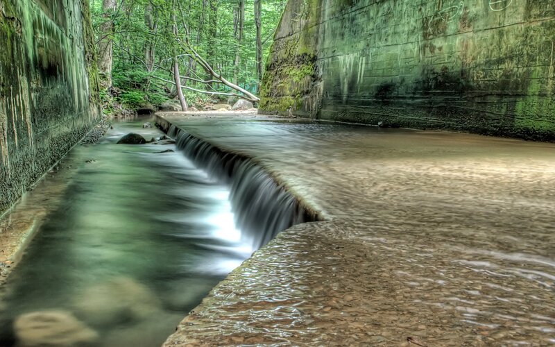 Stream Flowing Through Tunnel — Green, Serene, Afternoon, Photograph, Concrete Walls