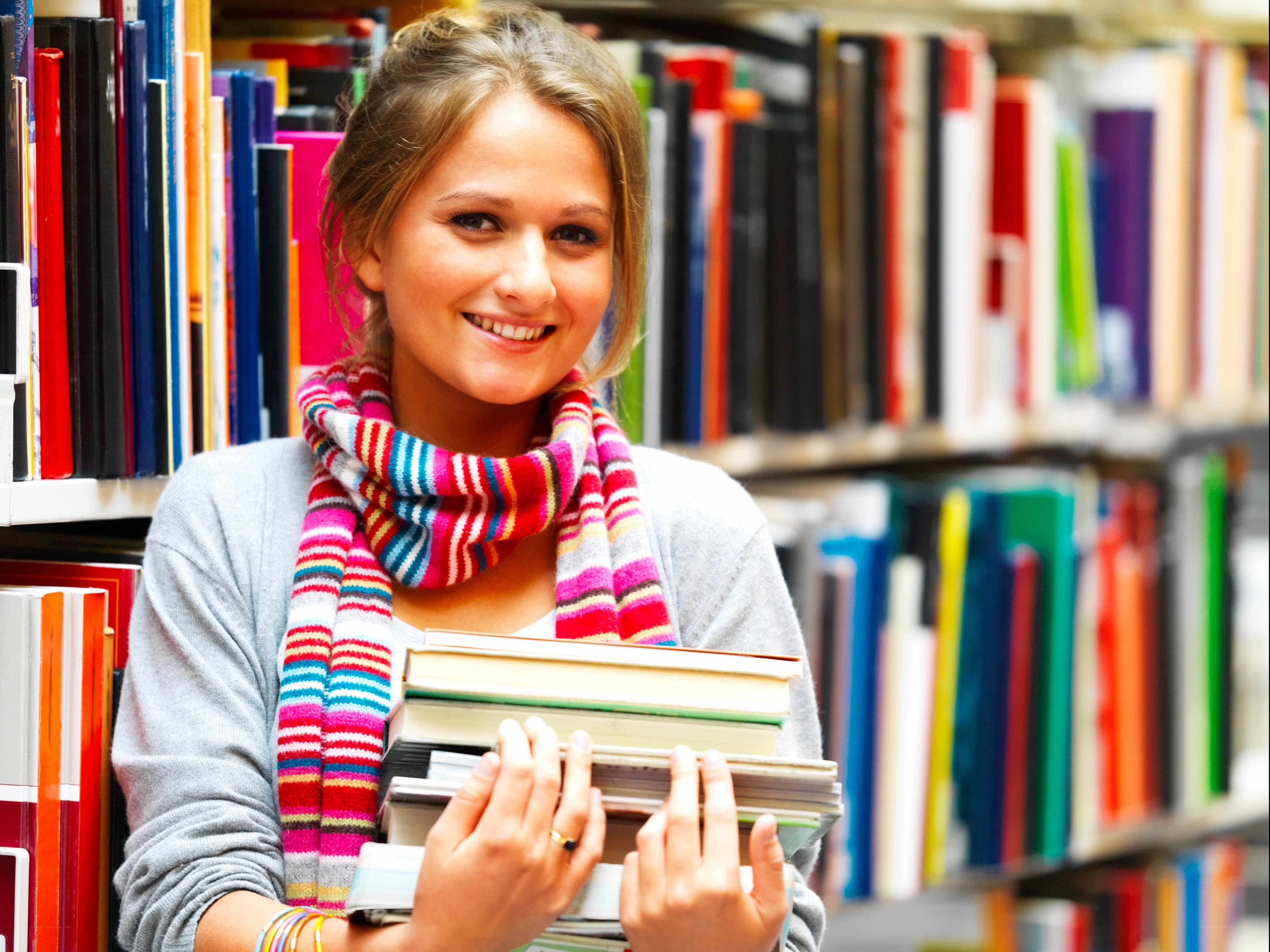 student holding books in library