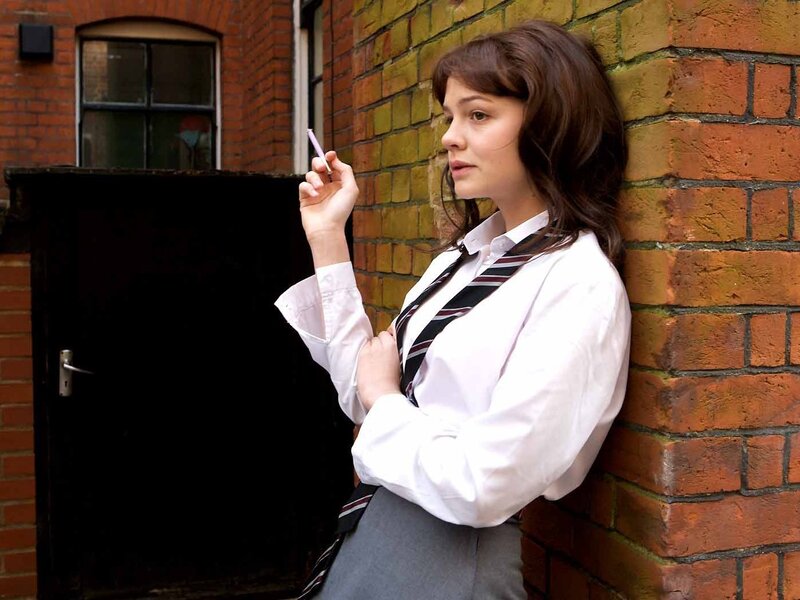 student leaning against brick wall