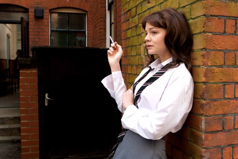 student leaning against brick wall