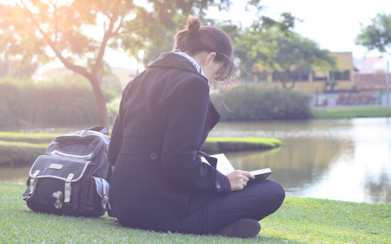 Student reading by a pond