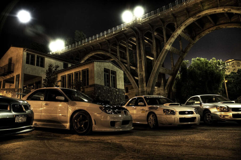 Subaru cars under a bridge at night