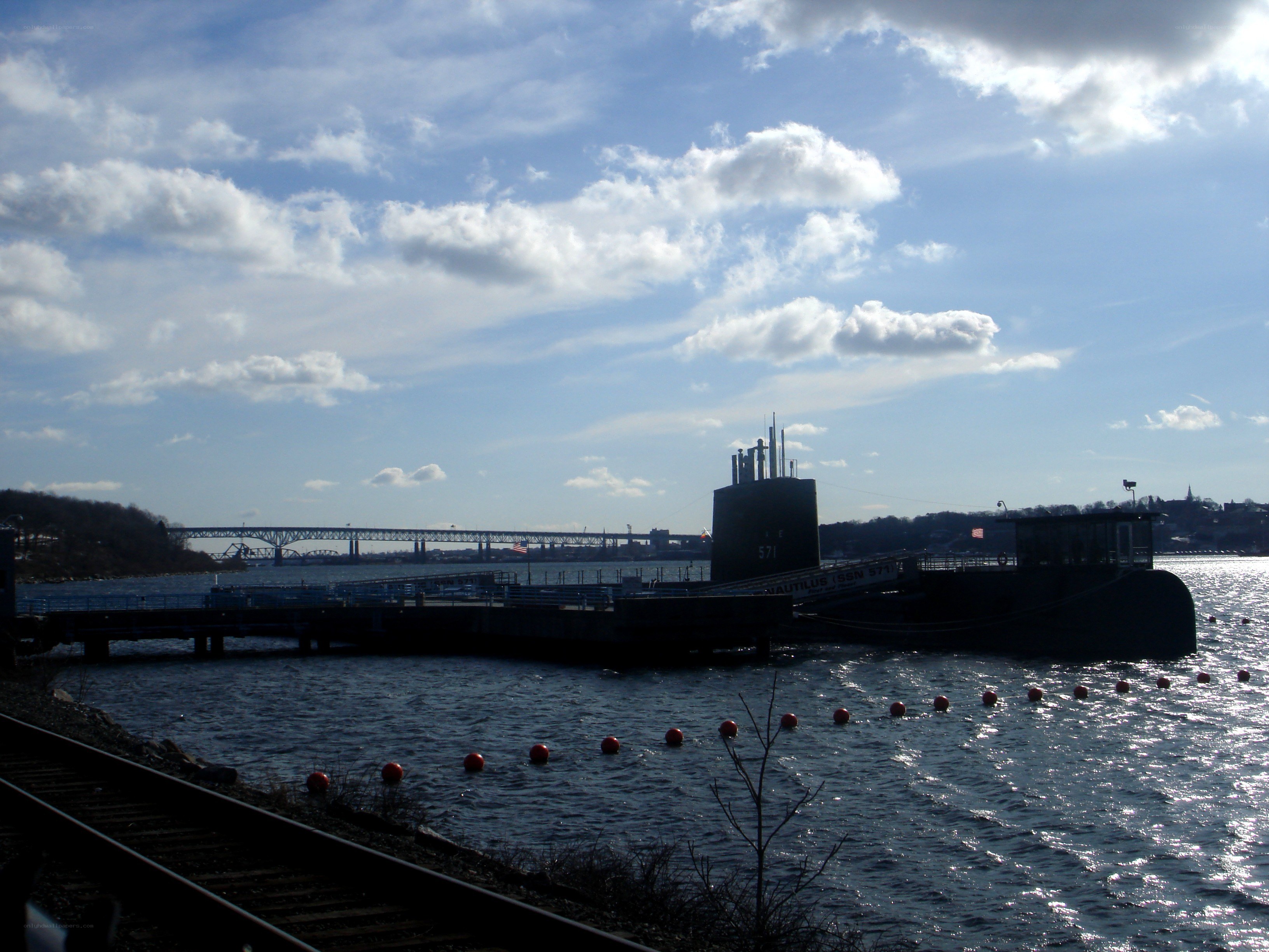 Submarine at dock with bridge in background