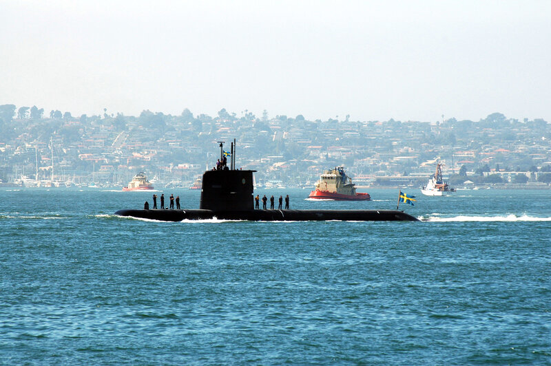 Submarine in harbor with support vessels