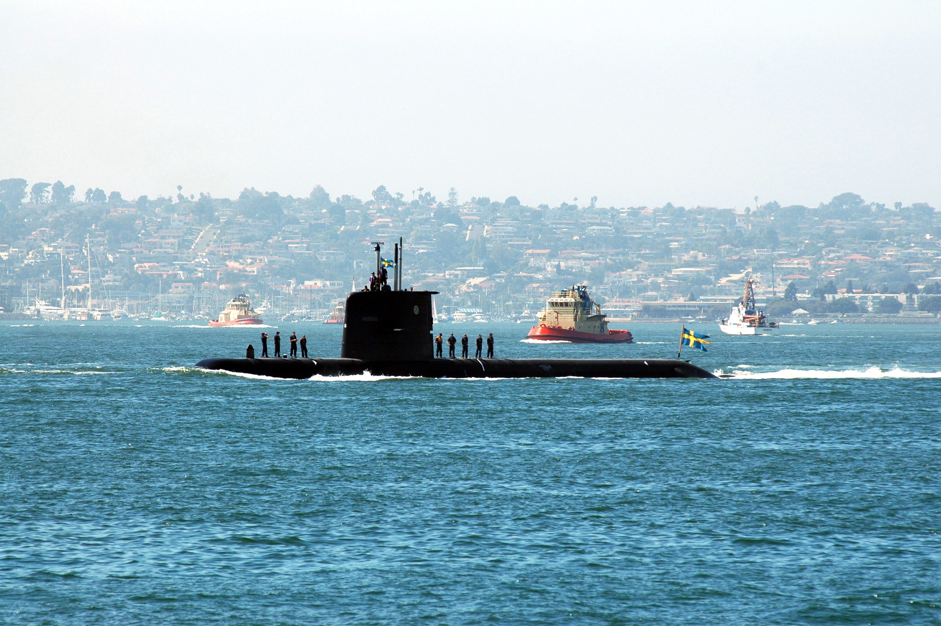 Submarine in harbor with support vessels