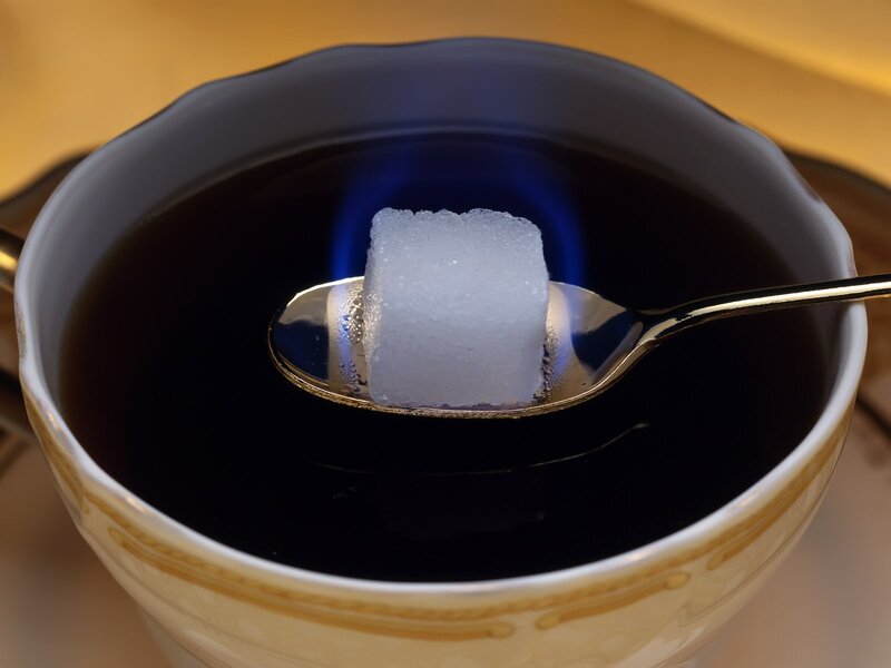 Sugar cube on spoon in tea
