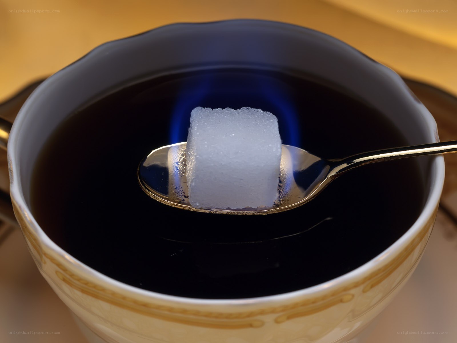 Sugar cube on spoon in tea