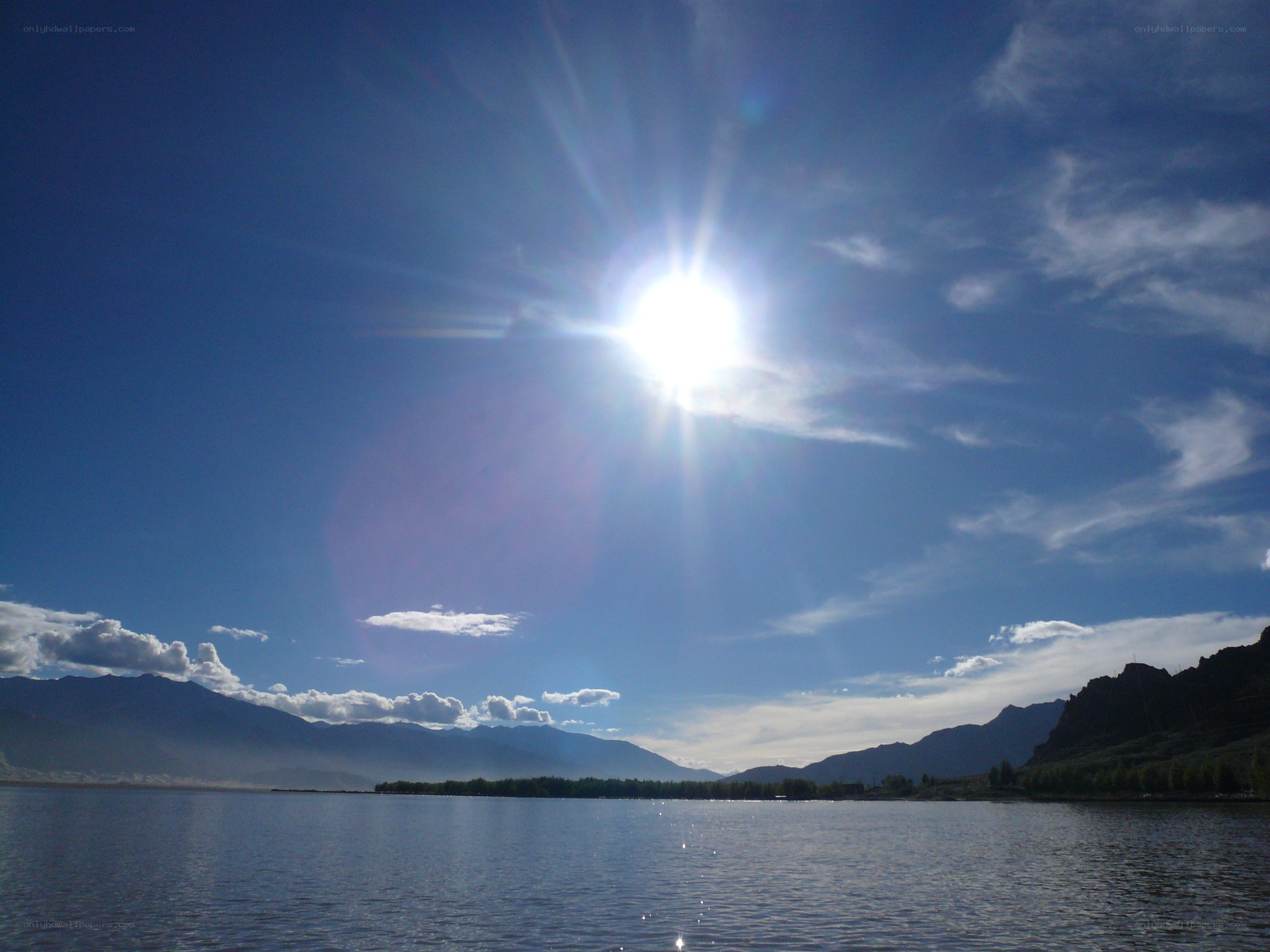 Sun over a lake and mountains