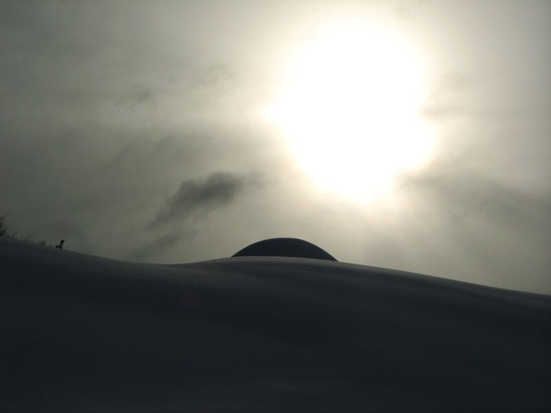 Sun over snowy hill