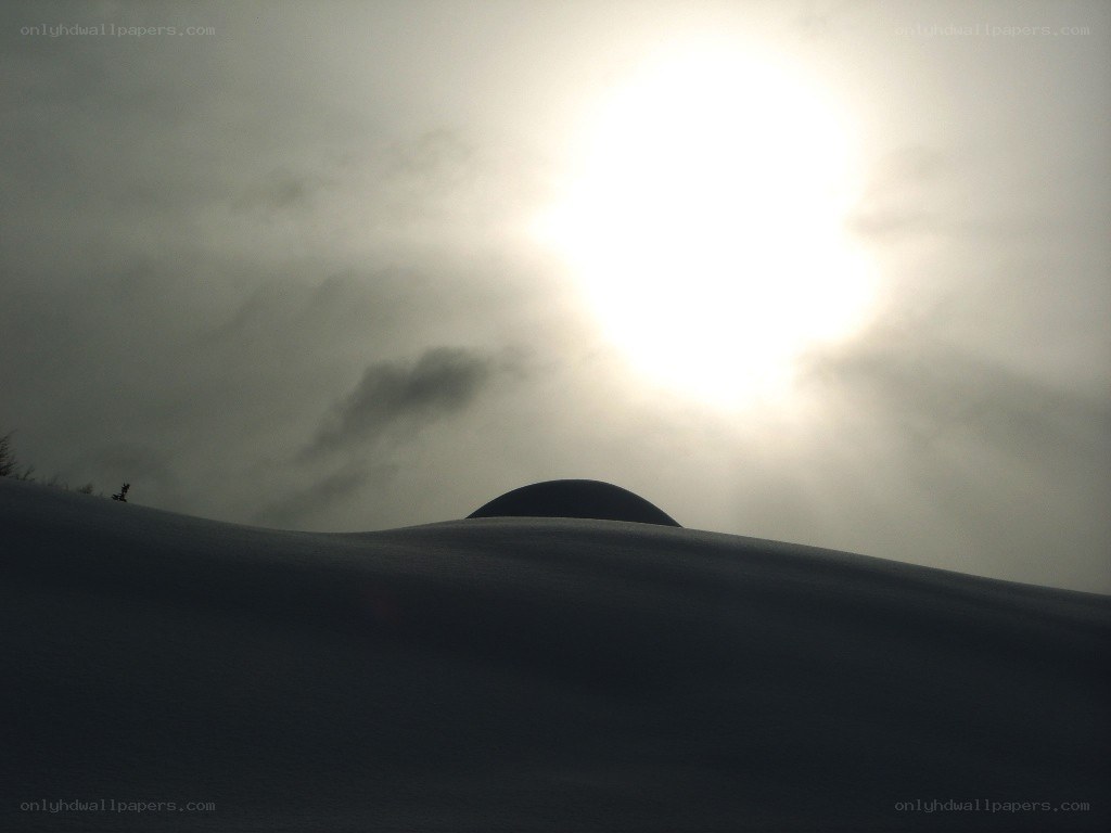 Sun over snowy hill