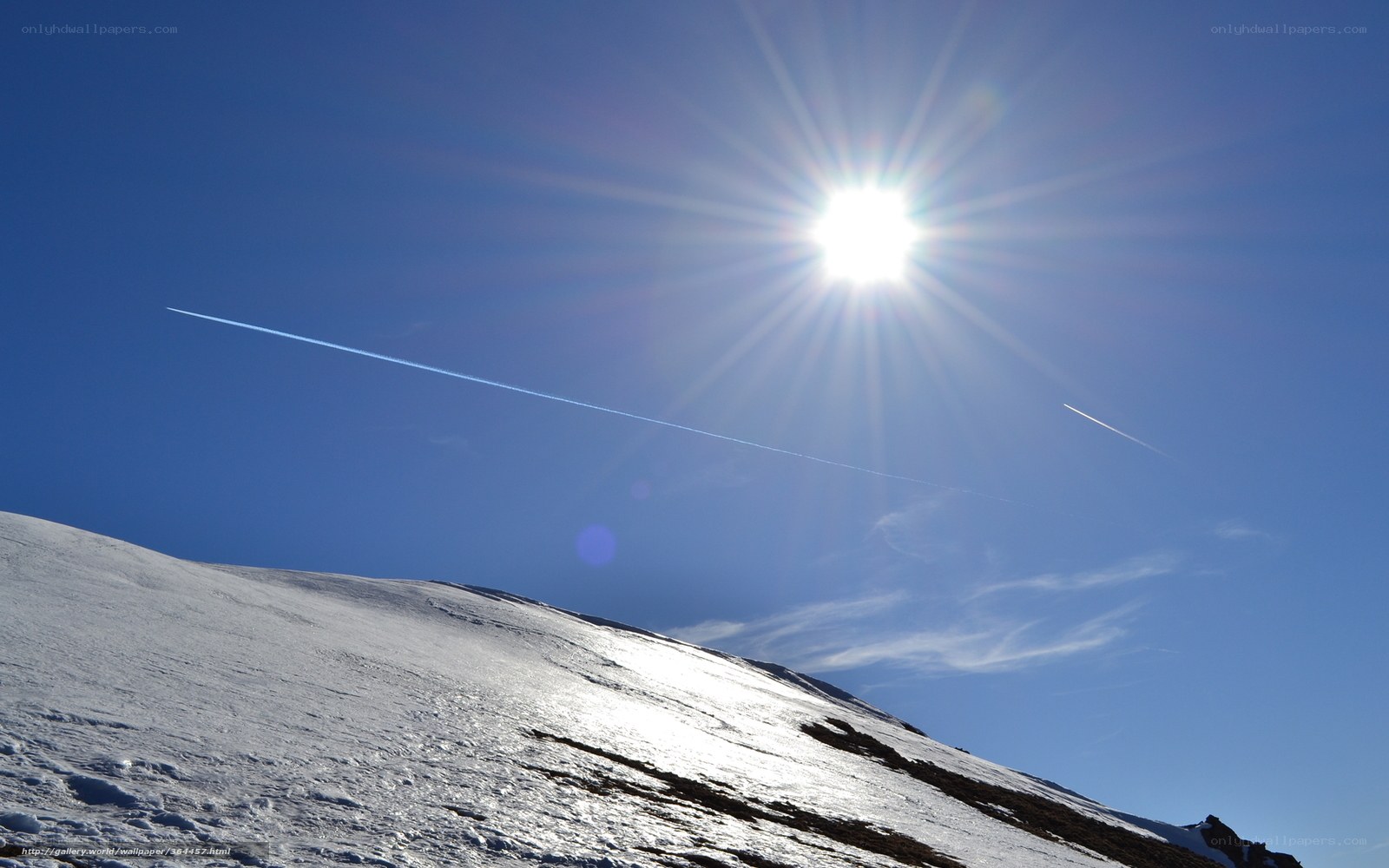 Sun over snowy mountain slope