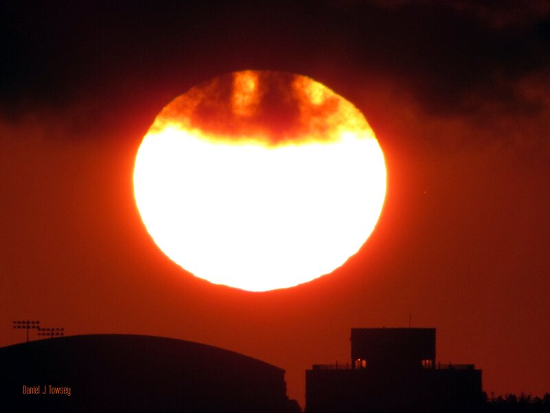 Sun Setting Behind Buildings — Red
